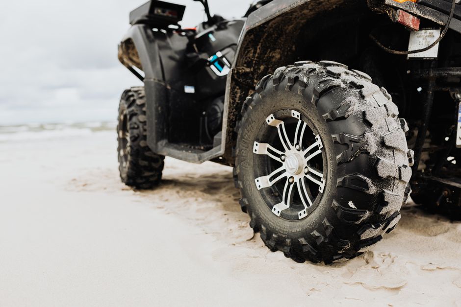 Close-up of an ATV tire on a sandy beach, showcasing rugged design and adventure capability.