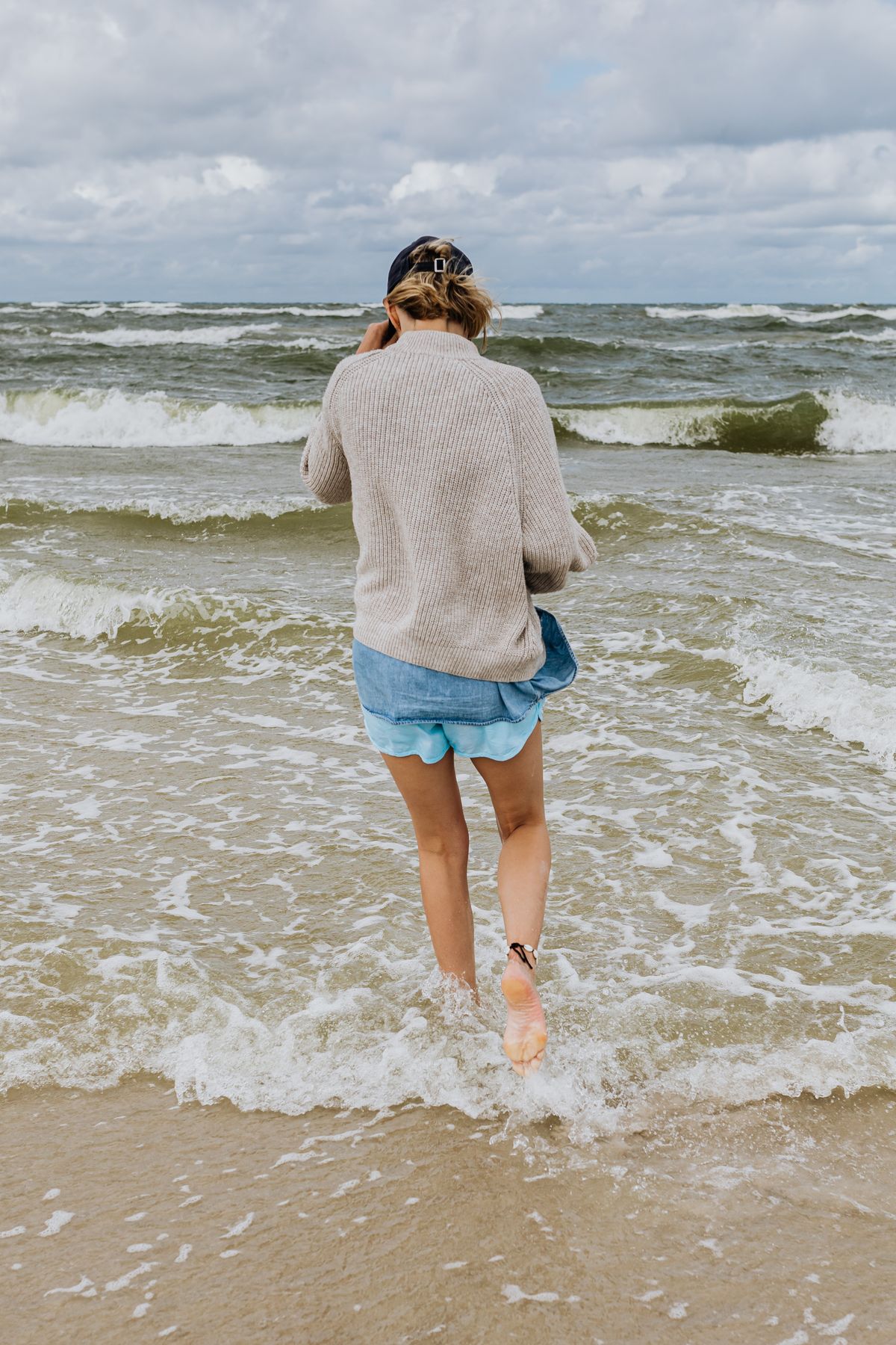 Back view of a woman walking on the beach in a fine knit — summer knit styling