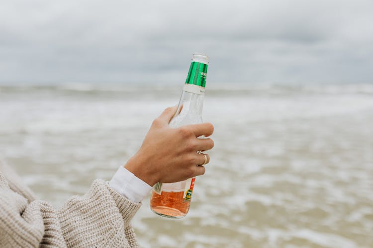 A Person In Knitted Sweater Holding A Bottle Of Beer