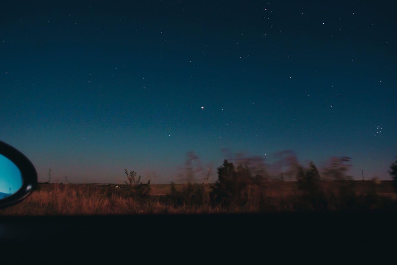 view through moving car window of horizon line with dark star sky and