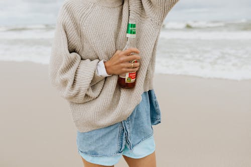 Person in Beige Sweater Holding a Beer