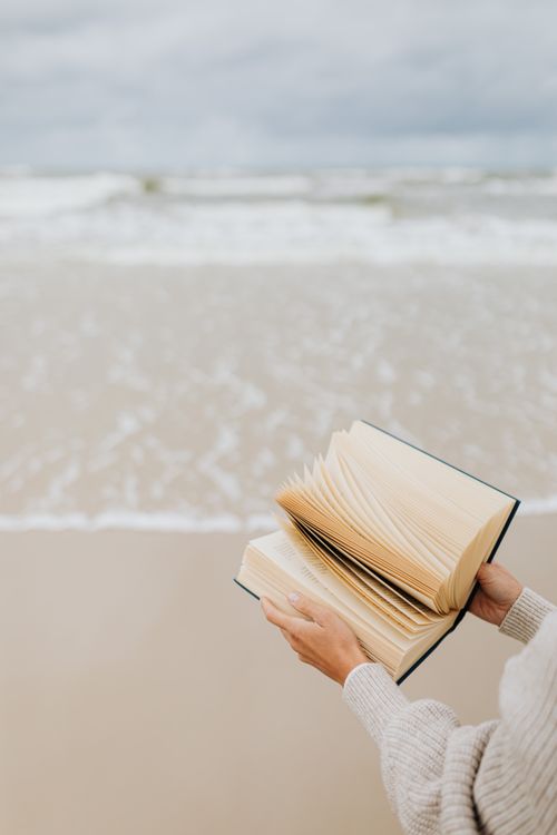 A person flipping pages of a book on the beach