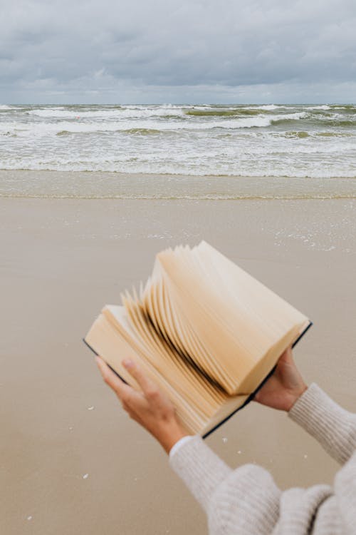 Person Holding a Book at the Beach
