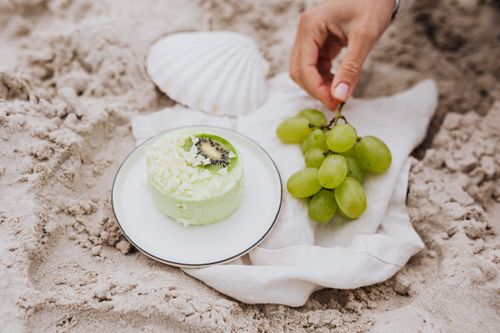 Free Close-up of a green dessert with grapes and shell on sandy beach. Stock Photo