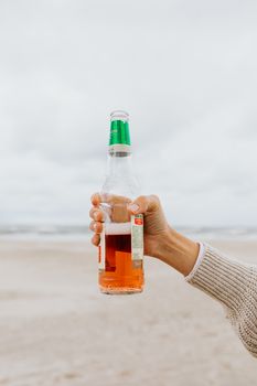 手拿啤酒瓶在沙滩上，捕捉清爽的夏日时刻