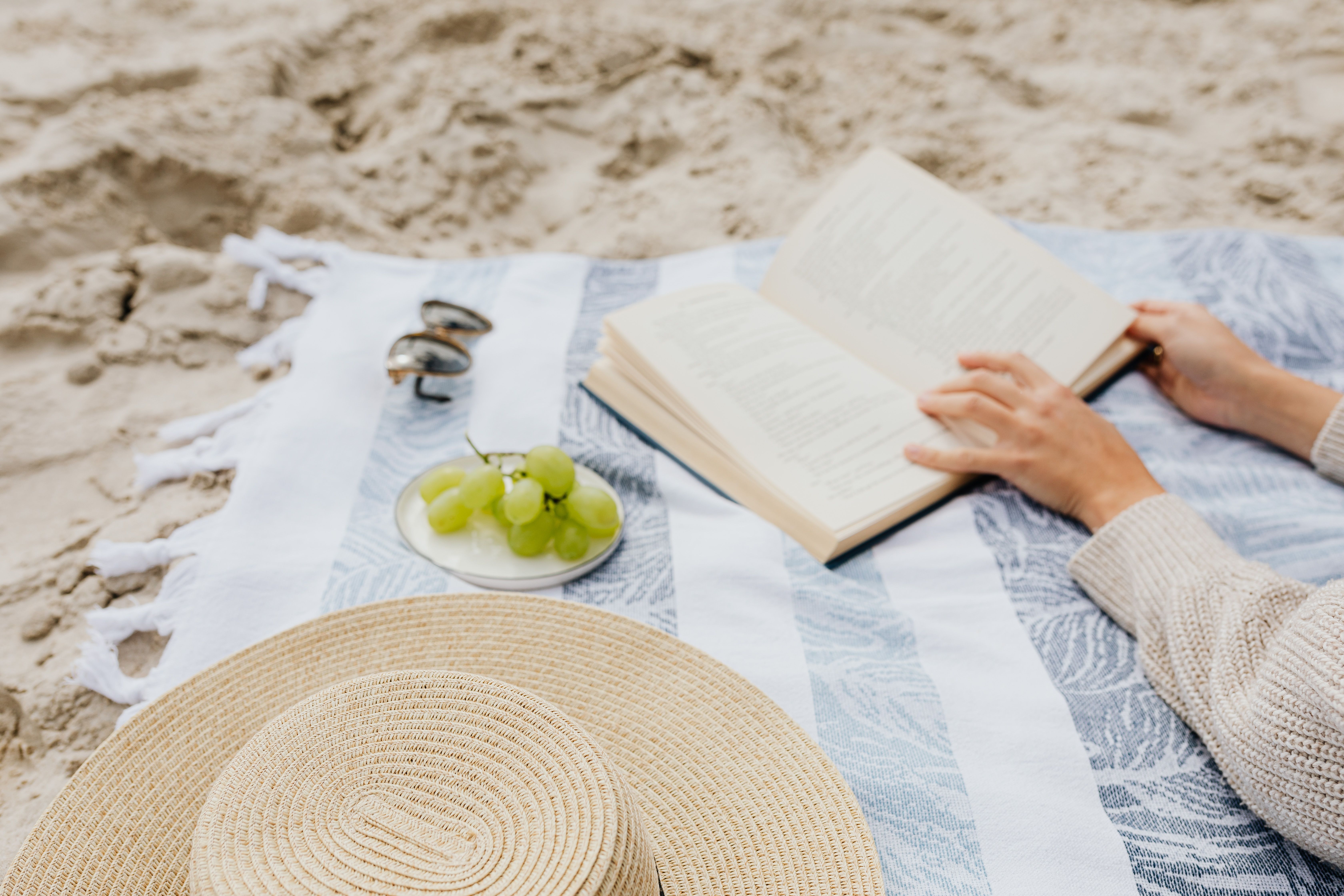 Relaxed beach scene with a book and sun hat on the sand