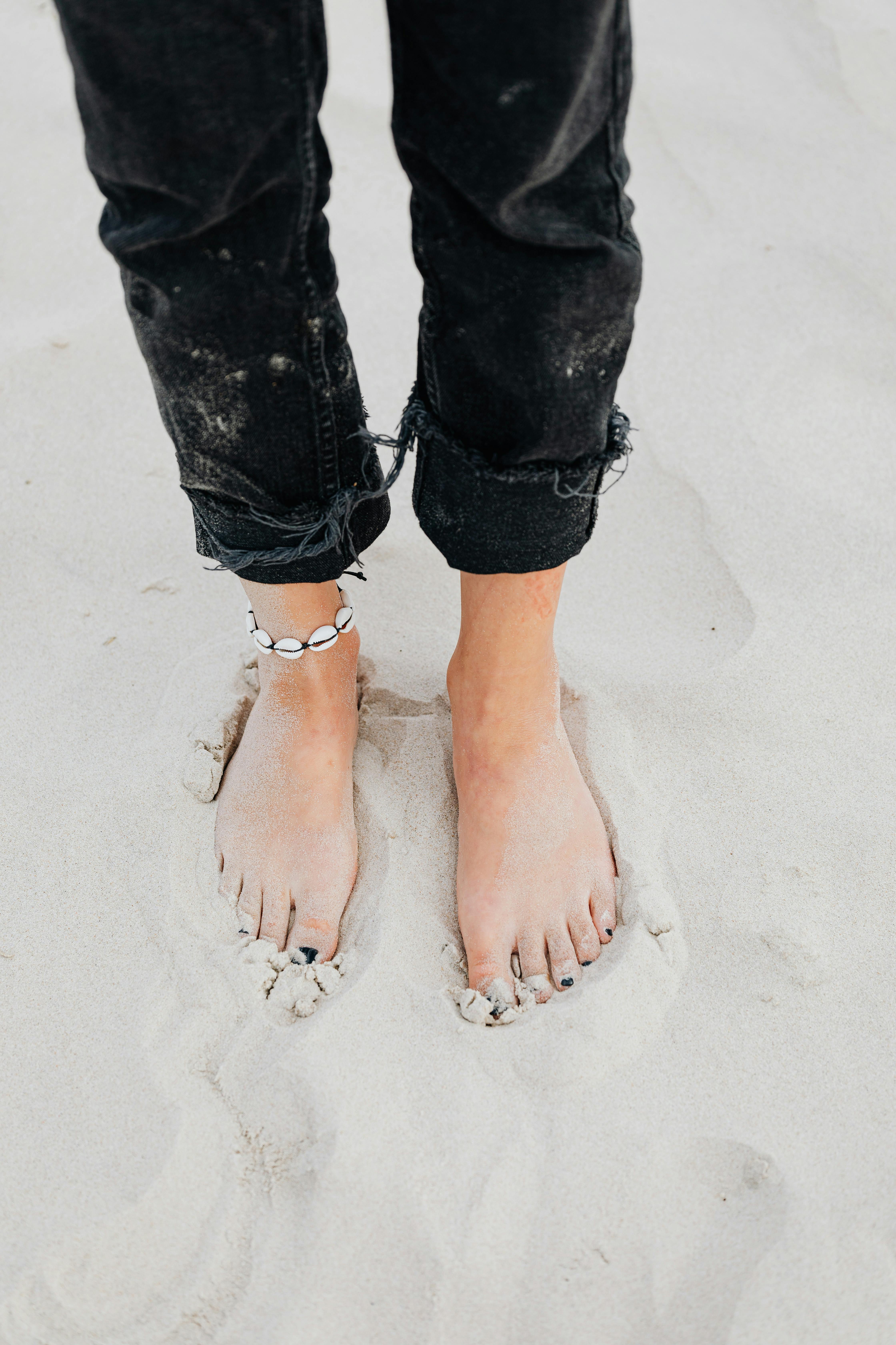 沙滩上赤脚腿和黑裤子的特写