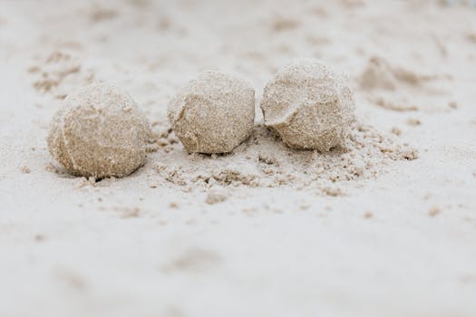 Three sand spheres resting closely on a beach showcasing the natural texture and form.