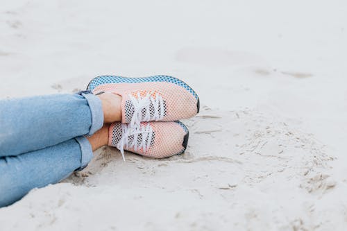 Free Person Wearing Orange Athletic Shoes on the Sandy Shore Stock Photo
