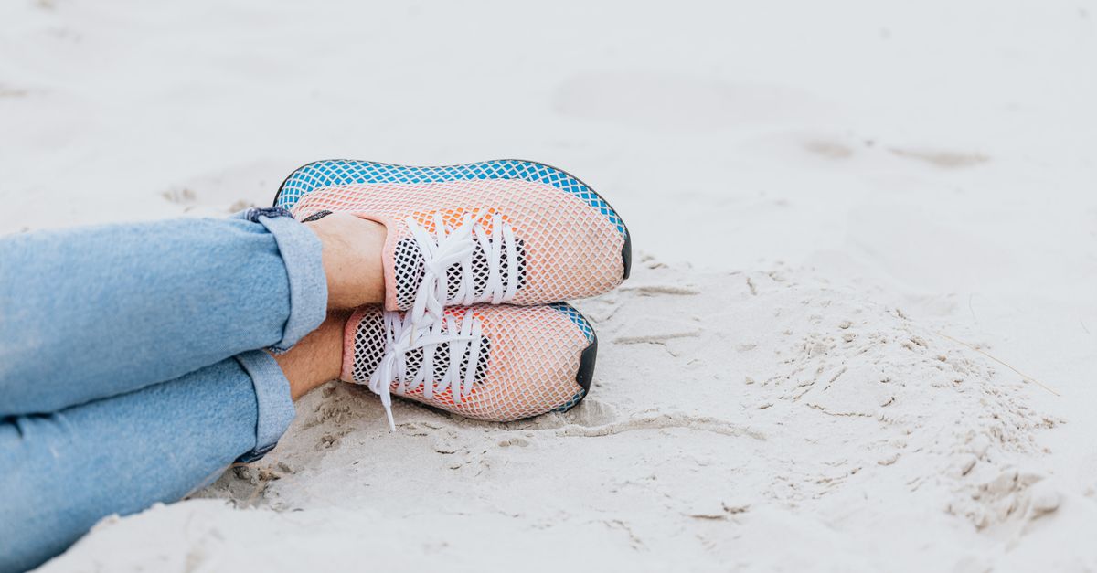 Casual beach day with denim jeans and sneakers on sandy shore. Comfortable and laid-back vibes.