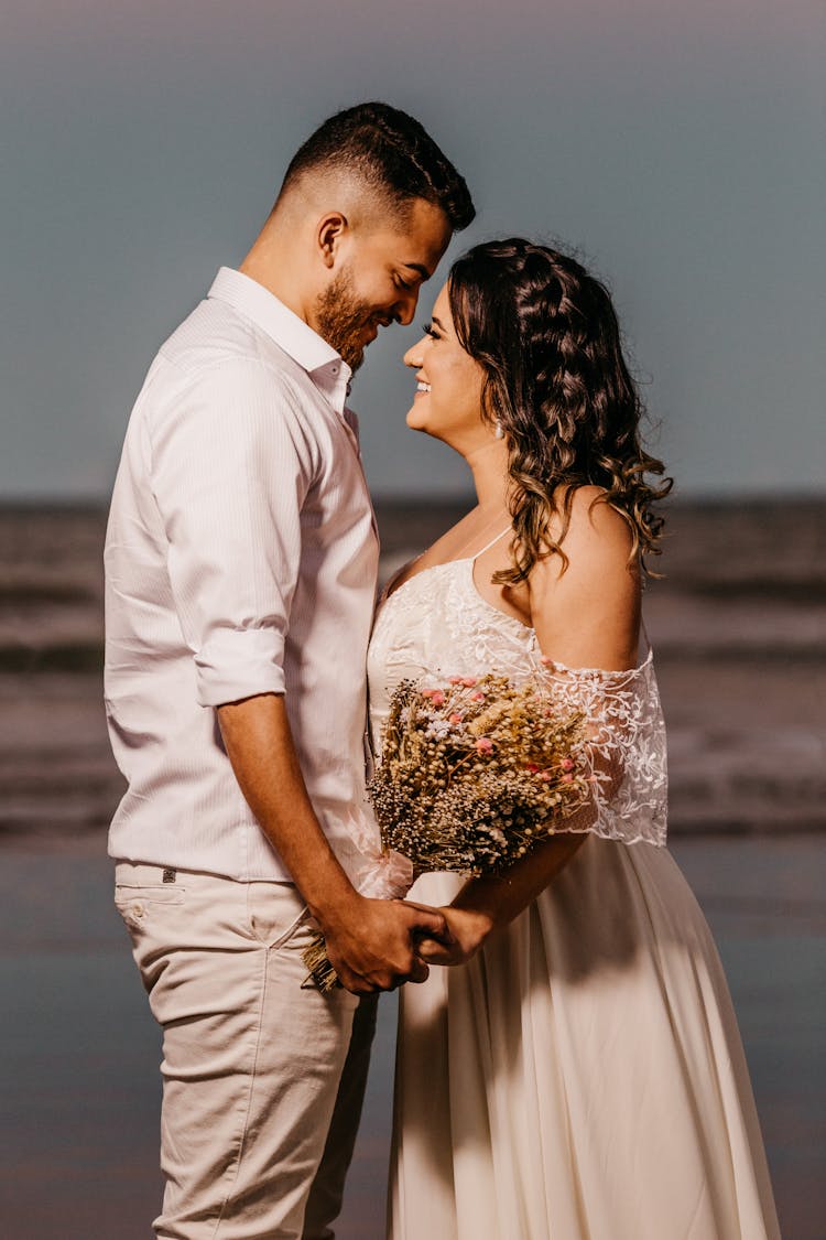 Romantic Young Ethnic Newlyweds Holding Hands On Sandy Seashore