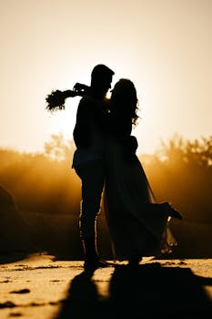 日落时分，沙滩上，一对幸福的年轻夫妇相拥的侧影剪影