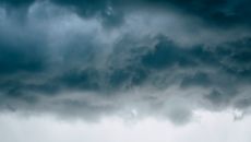 Fluffy dark rainy clouds floating in dramatic gray sky in stormy rainy weather
