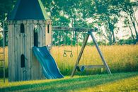 Timber tower with sway and chute near meadow with trees and lush verdant grass