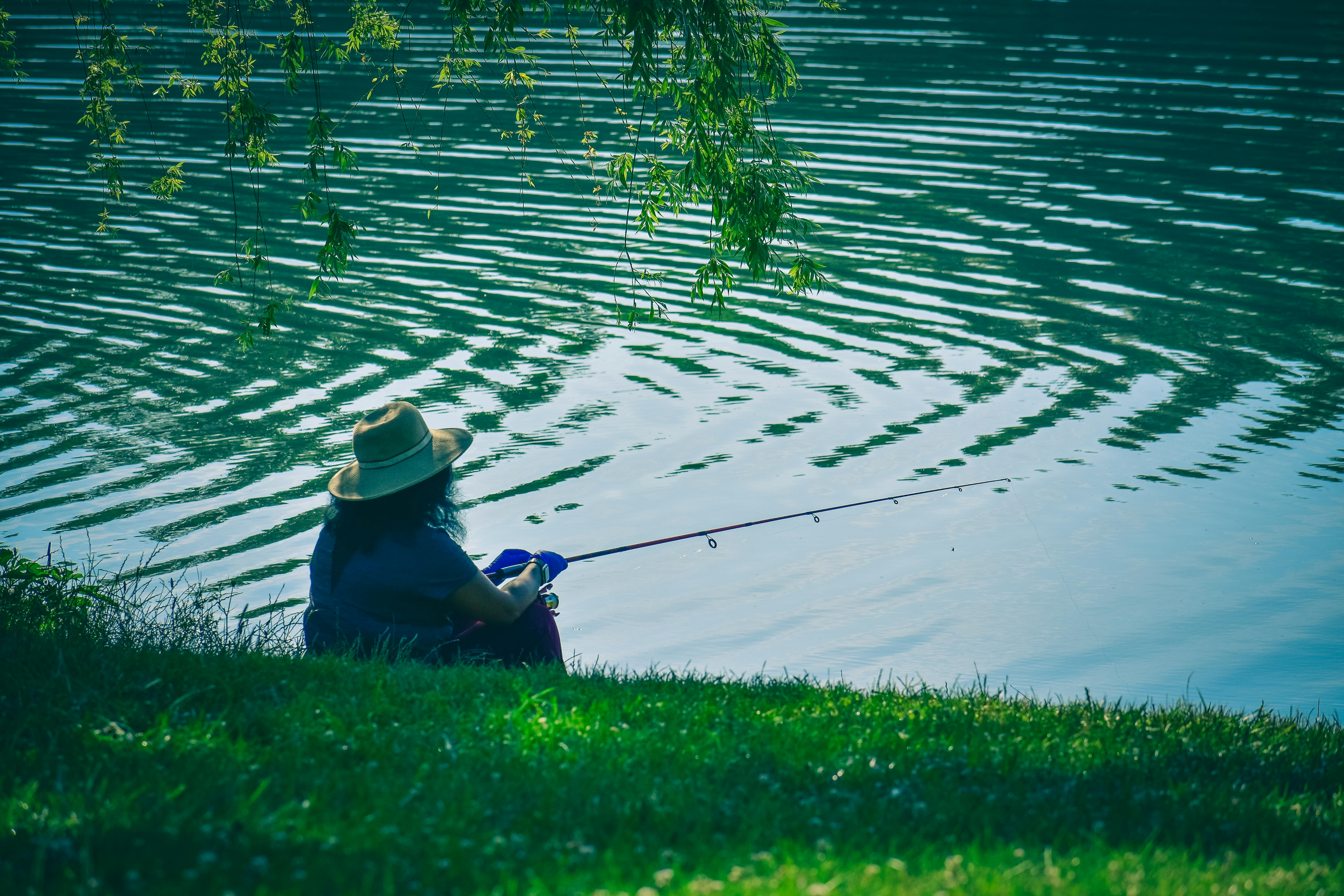 Download Man fishing at a serene lake with a high-quality fishing