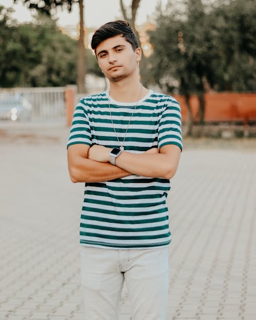 Selective Focus Photo of a Man in a Striped Shirt Posing with His Arms Crossed