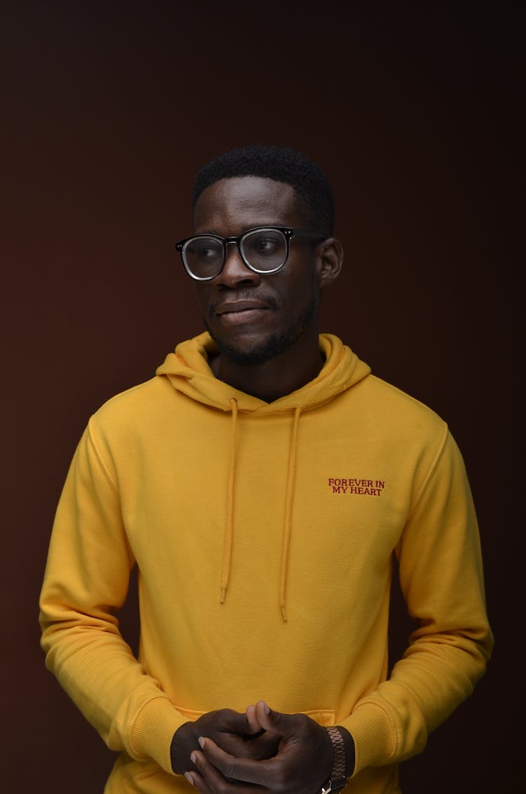 Stylish Young Black Man In Yellow Hoodie In Red Studio