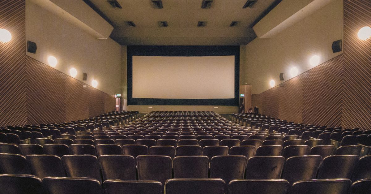 A vacant theater showing rows of seats and a large screen.