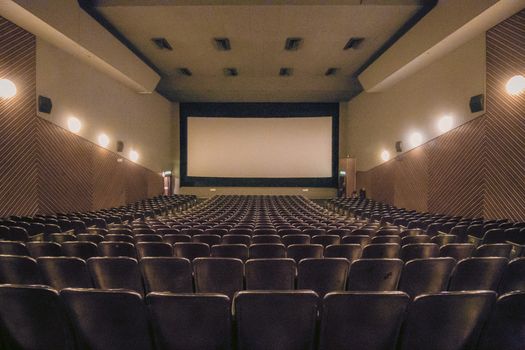 A vacant theater showing rows of seats and a large screen.