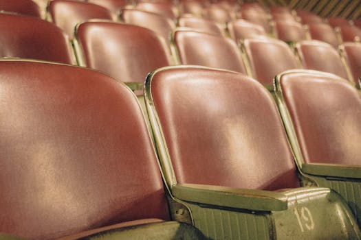Detailed view of empty red theater seats arranged in rows within an auditorium.