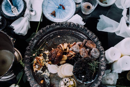 Top view of assorted delicious dried with cheese fruits on tray served on table near dishware and candles during festive dinner