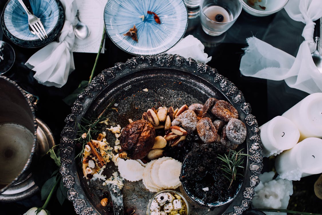 Top view of assorted delicious dried with cheese fruits on tray served on table near dishware and candles during festive dinner