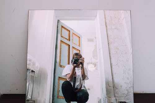 Photographer with photo camera taking selfie in mirror