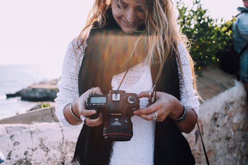 Happy woman checking photos on camera near sea