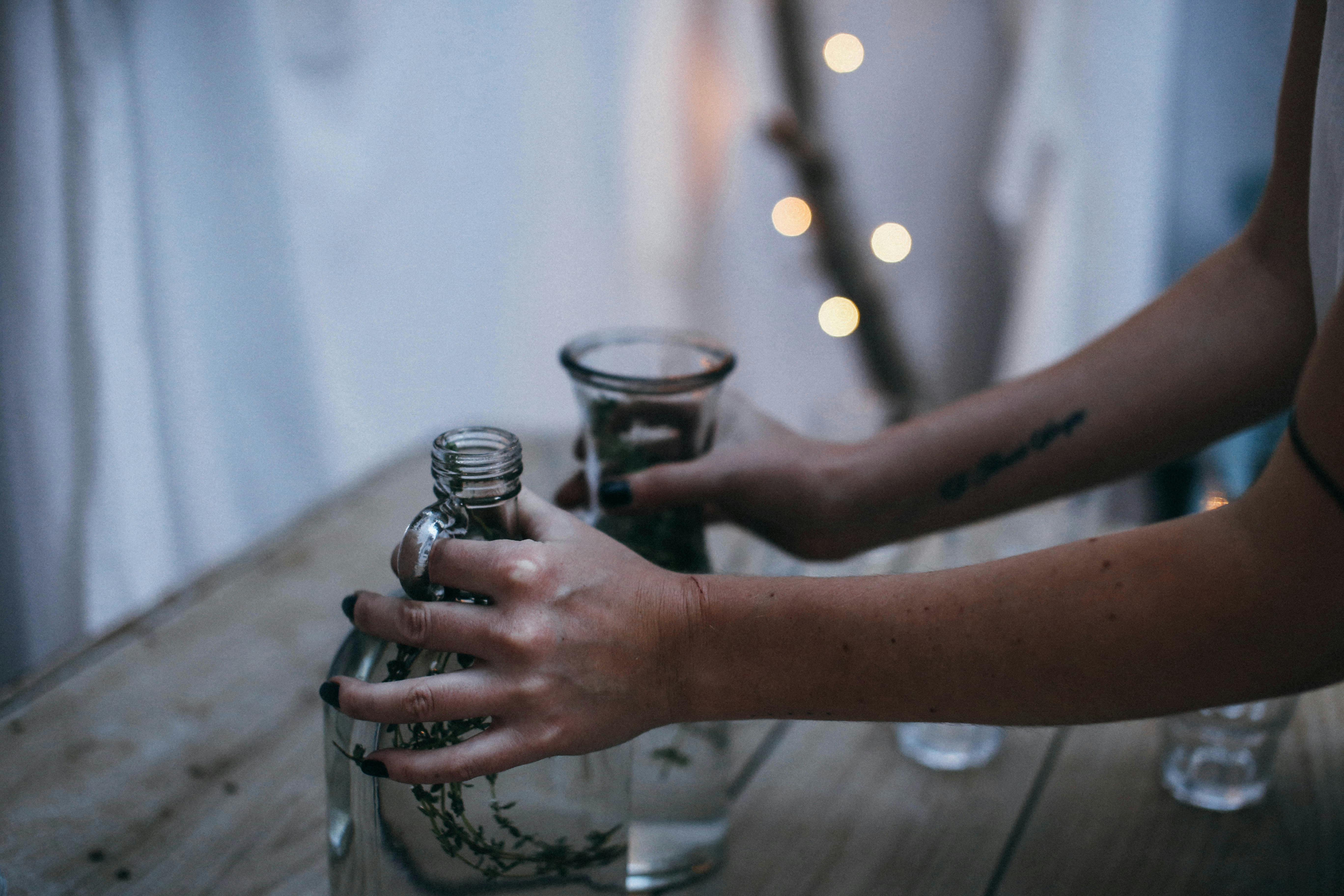 crop unrecognizable woman putting glass vases on table