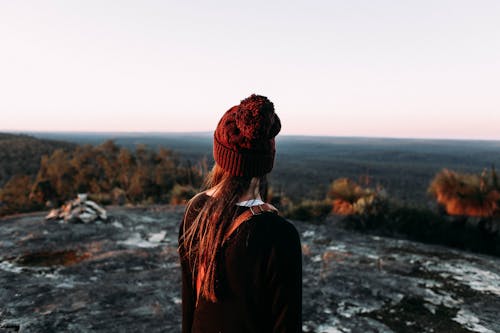 Anonymous female traveler on hill admiring valley with forest