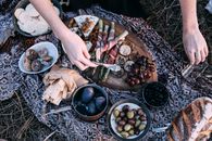 在乡村户外环境中，优雅的野餐设施将各种食物铺在毯子上