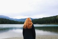 一名女子站在群山环绕的宁静湖畔，享受着这份宁静