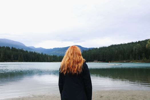 一名女子站在群山环绕的宁静湖畔，享受着这份宁静