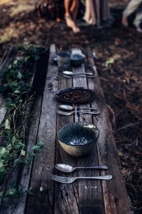 Table setting placed on wooden bench in forest