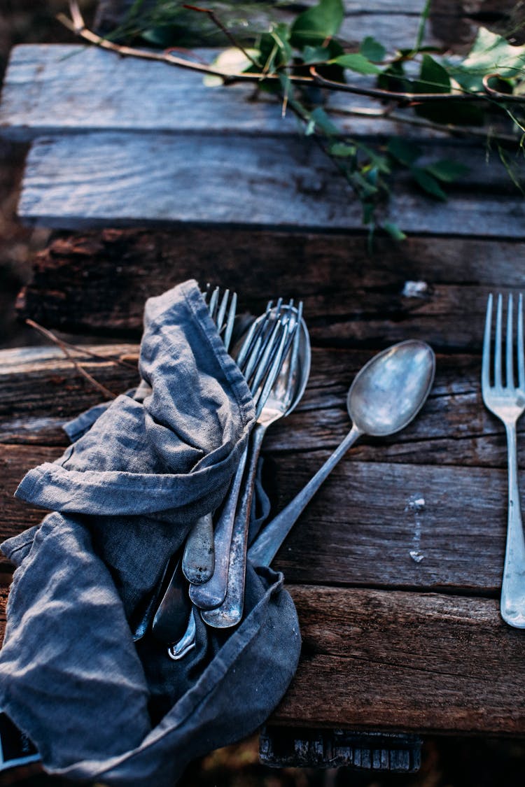 Cutlery On Crumpled Cloth On Wooden Table