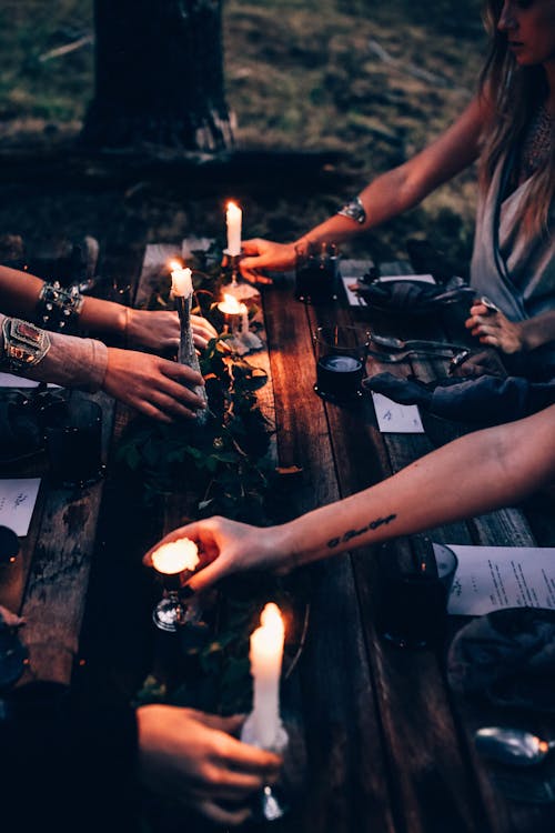 Free Crop fortune tellers with burning candles at table outdoors Stock Photo