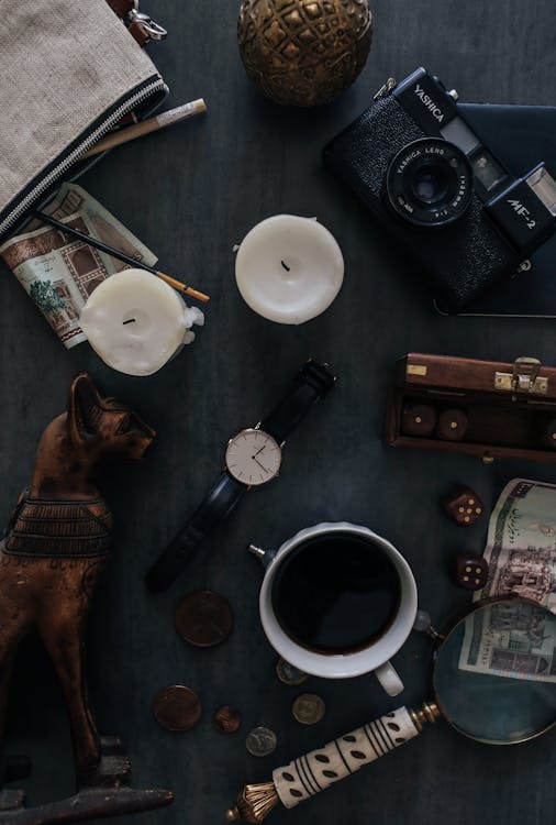 Top view of retro photo camera near wristwatch and dog statuette with hot drink on table