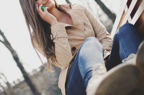 무료 여자가 벤치에 앉아있는 동안 스마트 폰 들고 스톡 사진