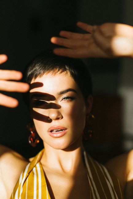 A captivating portrait of a short-haired woman with sunlight casting shadows on her face.