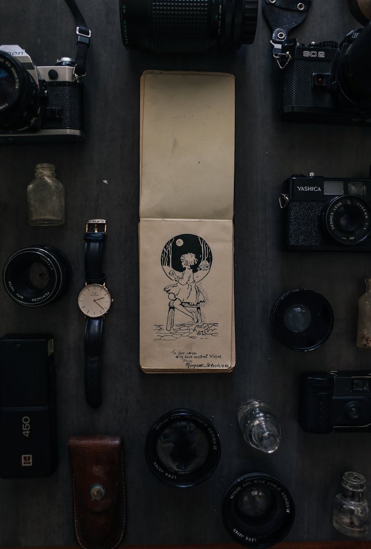 Vintage Notebook Among Photo Cameras On Table