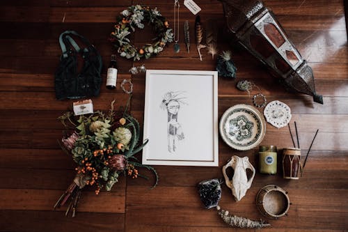 Top view of frame with illustration among flower bouquet and lantern near amulets on wooden surface