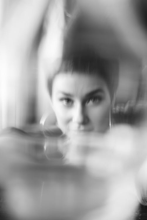 Black and white of young friendly female with short hair in accessories looking at camera