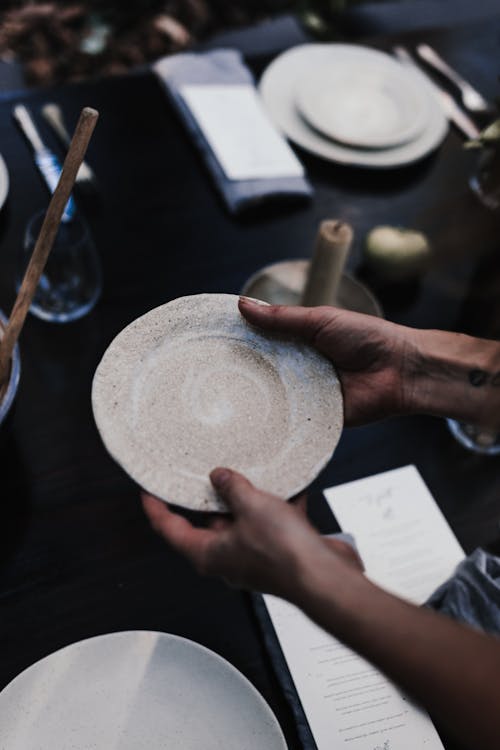 Crop person with plate above served table