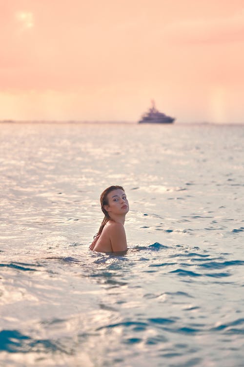Relaxed young lady swimming in sea at sunset