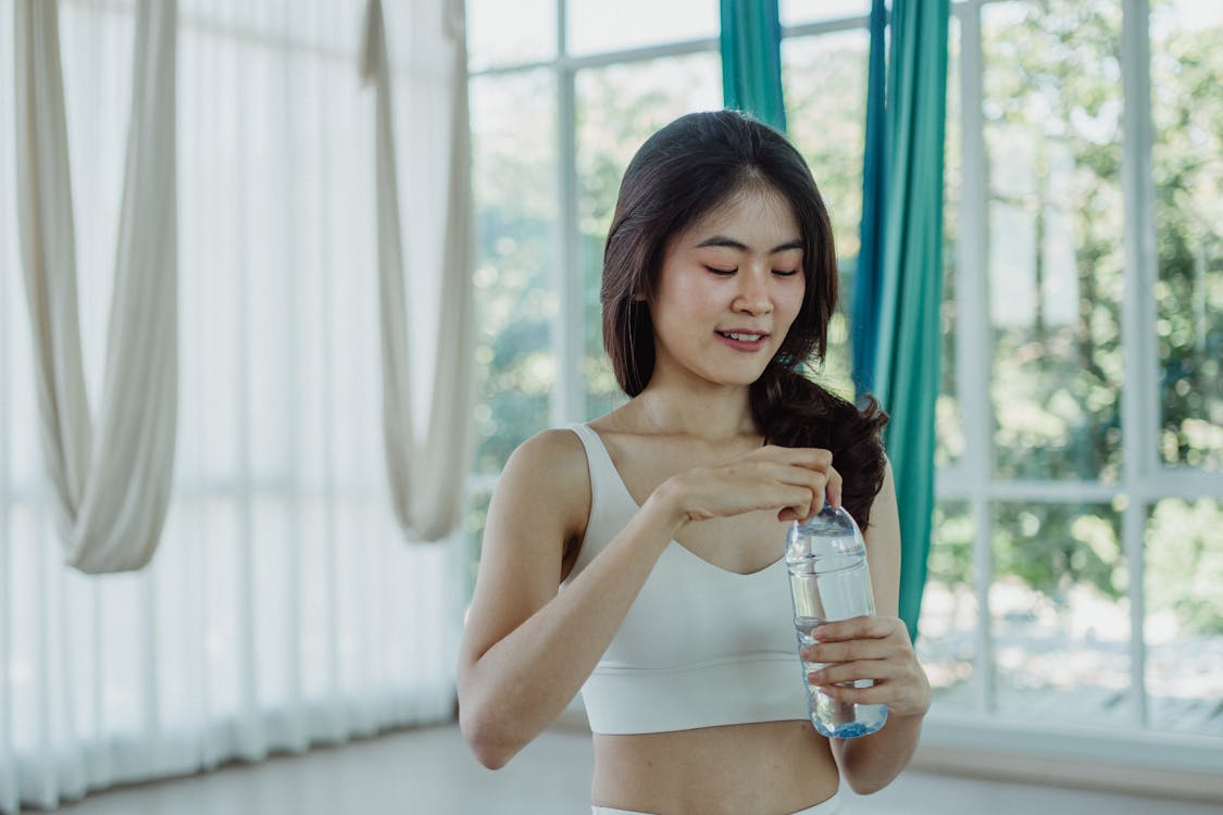 Woman in White Sports Bra Holding a Water Bottle