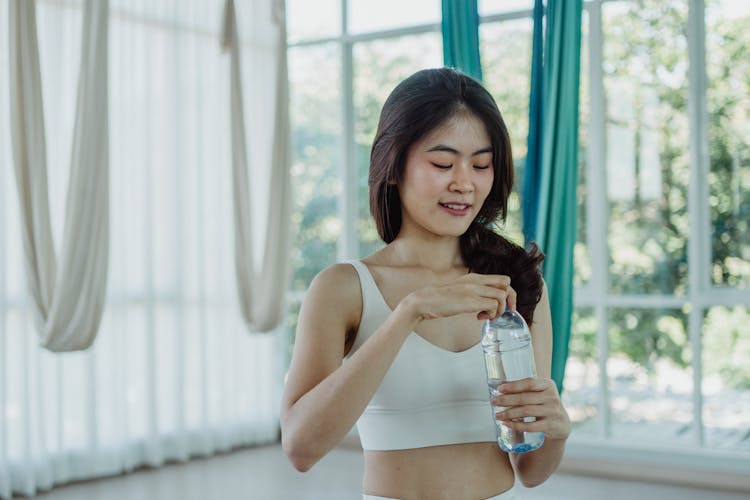 Woman In White Sports Bra Holding A Water Bottle