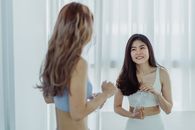 两名穿着健身服的妇女拿着水瓶，在室内微笑着享受锻炼后的休息