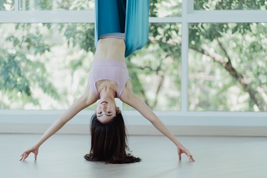 Woman performing aerial yoga in a bright indoor studio. Perfect for wellness and fitness themes.