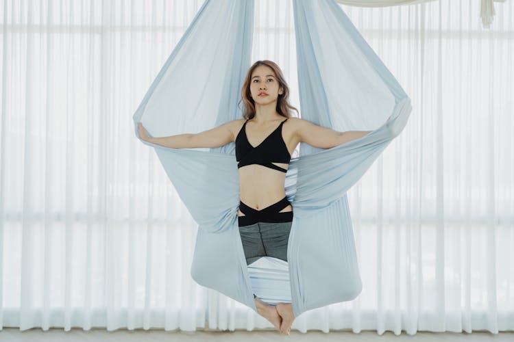 Woman In Black Sports Bra And Leggings Stretching On Hanging Cloth