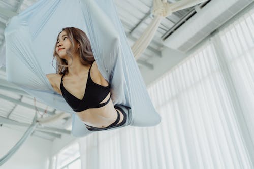Low-Angle Shot of Woman Doing Aerial Yoga Inside the Studio